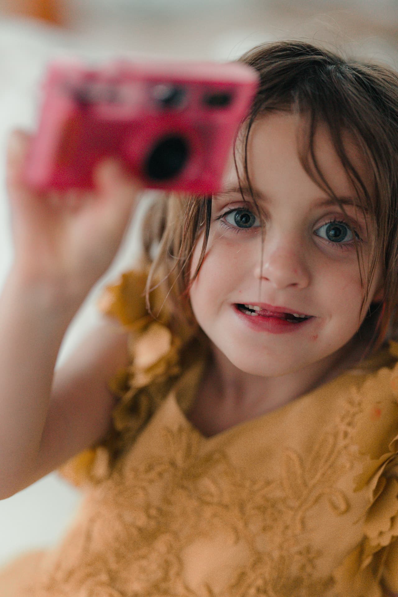 A girl holding up a pink camera close to the lens — photo by Kathy