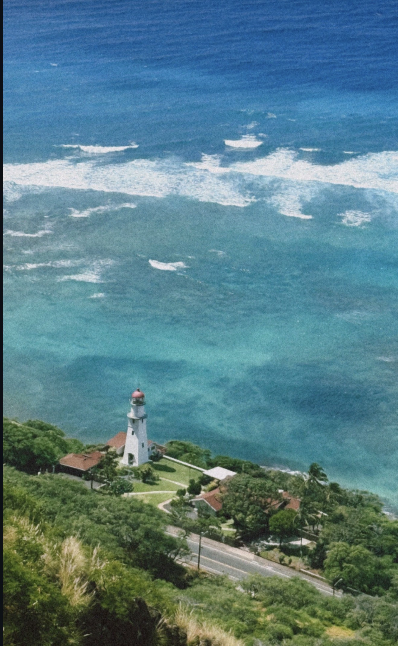 A white lighthouse above turquoise ocean water — photo by Kathy