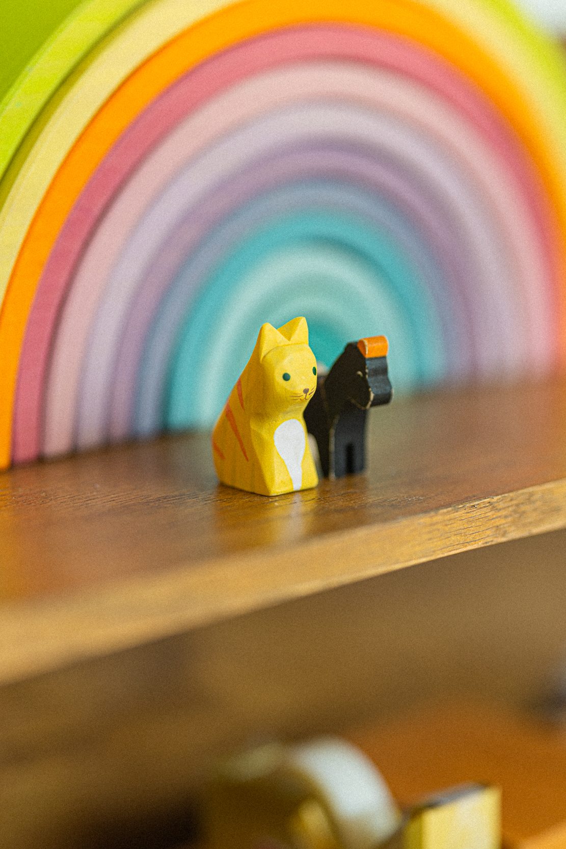A wooden rainbow with painted animals on a shelf — photo by Kathy