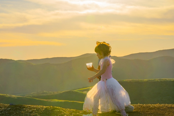 A girl holding a cup at sunset in the hills