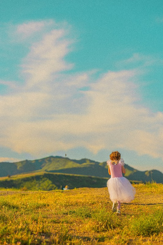 A girl in a twirly dress walking toward the hills